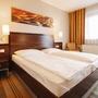 Hotelzimmer mit Doppelbett in modernem Design, helle Farben und großem Fenster.