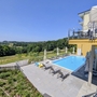 Hotelpool mit Liegestühlen und Blick auf grüne Landschaft bei Laßnitzhöhe.