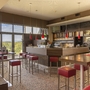Moderne Hotelbar mit roten Barhockern und großer Fensterfront.