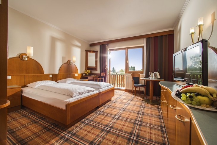 Hotelzimmer mit Doppelbett, Fensterblick und Obstteller auf einem Tisch.