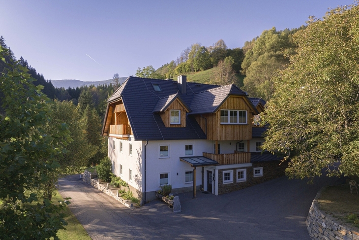 Großes, traditionelles Gebäude in ruhiger, bewaldeter Berglandschaft.