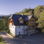 Großes, traditionelles Gebäude in ruhiger, bewaldeter Berglandschaft.