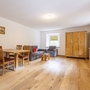 Wohnzimmer mit Essbereich, Holzboden, Schrank, Sofa und Fernseher.