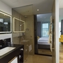 Modernes Hotelzimmer mit Glasdusche, Doppelbett und gelbem Sessel.