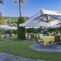 Garten des Hotels Regina Palace in Stresa mit Tischen, Stühlen und Sonnenschirmen