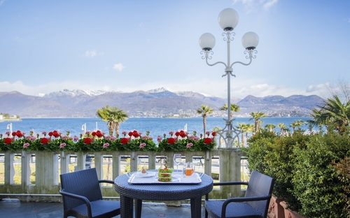 Blick auf gedeckten Tisch mit Stühlen und Seepanorama im Hotel Regina Palace, Stresa.