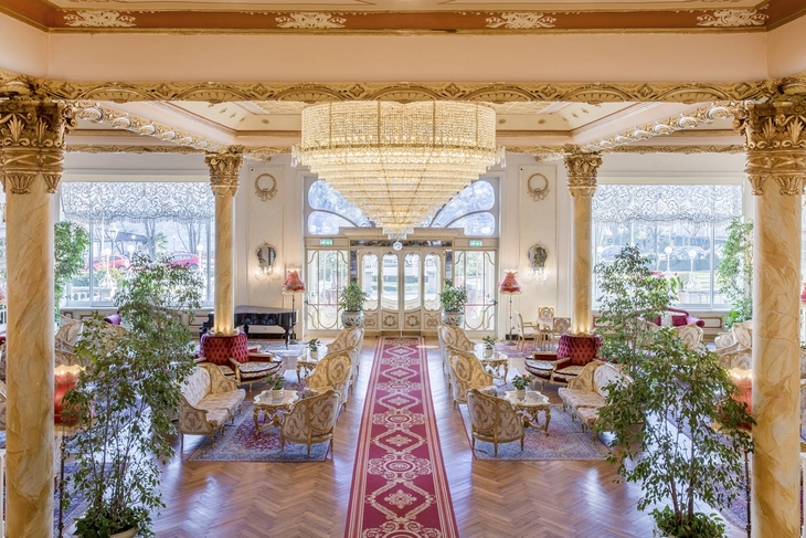 Luxuriöse Hotellobby mit prächtigen Säulen und elegantem Kronleuchter.