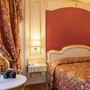 Luxuriöses Hotelzimmer mit Blumen, Vorhängen und Bett in Rot-Gold-Tönen.