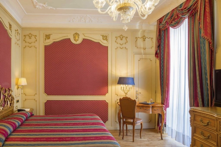 Hotelzimmer mit luxuriöser Einrichtung und bunten Vorhängen im Regina Palace Hotel.
