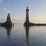 Hafeneinfahrt von Lindau mit Löwenstatue und Leuchtturm im Winter bei ruhigem Wasser