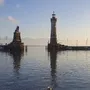 Hafeneinfahrt von Lindau mit Löwenstatue und Leuchtturm im Winter bei ruhigem Wasser