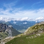 Aussicht auf Berglandschaft mit Seilbahn und Wanderweg bei Sonnenschein.