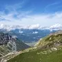 Aussicht auf Berglandschaft mit Seilbahn und Wanderweg bei Sonnenschein.