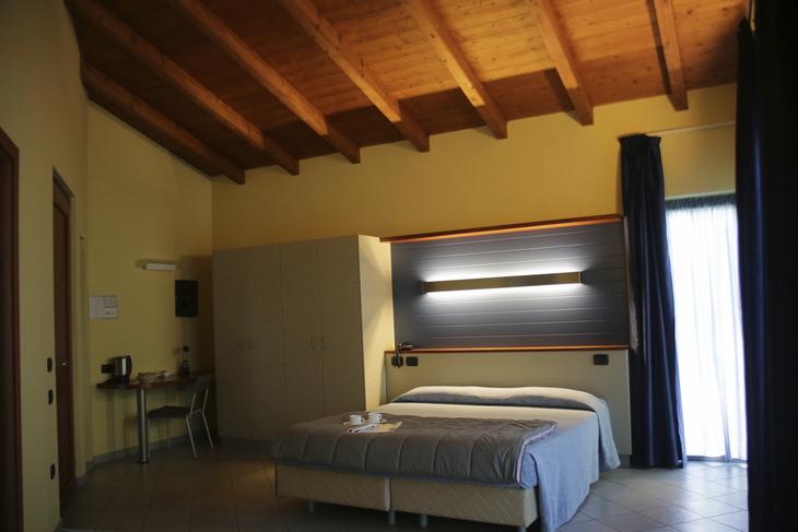 Hotelzimmer mit Doppelbett, Holzbalkendecke und Schreibtisch.