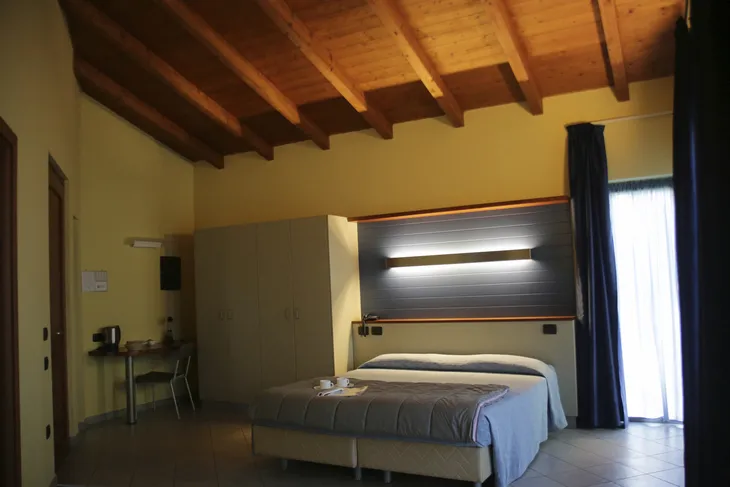 Hotelzimmer mit Doppelbett, Holzbalkendecke und Schreibtisch.