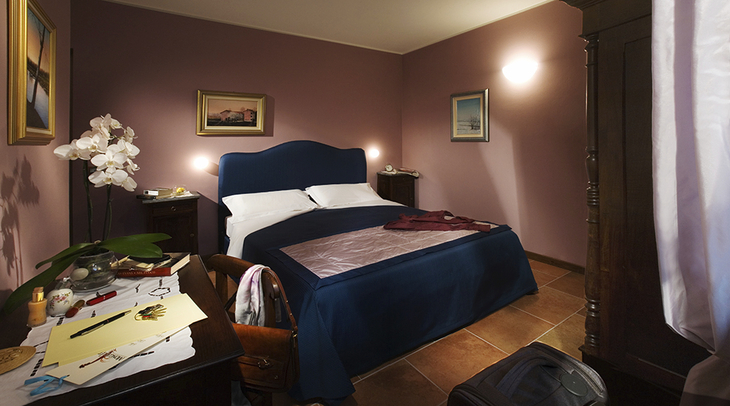 Doppelzimmer mit blauen Möbeln und lila Wänden im Agriturismo Mongalletto.