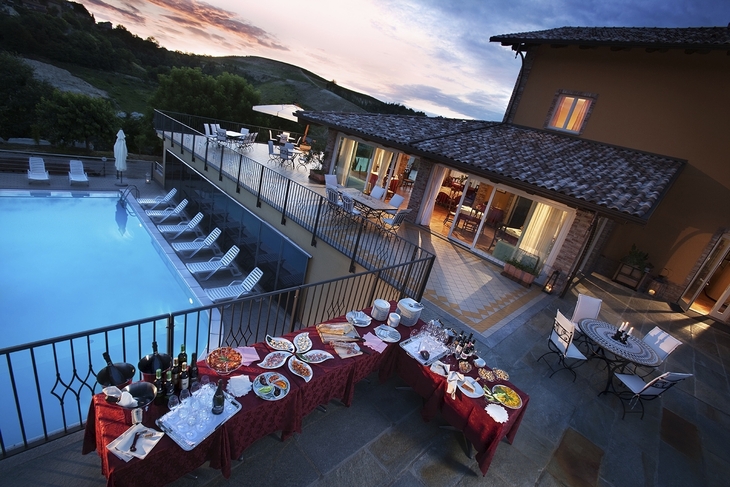 Terrasse mit Pool und gedeckten Tischen bei Abenddämmerung in Italien.