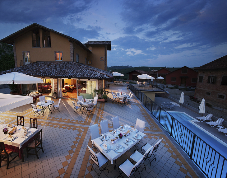 Terrasse eines Agriturismo mit gedeckten Tischen bei Abenddämmerung.
