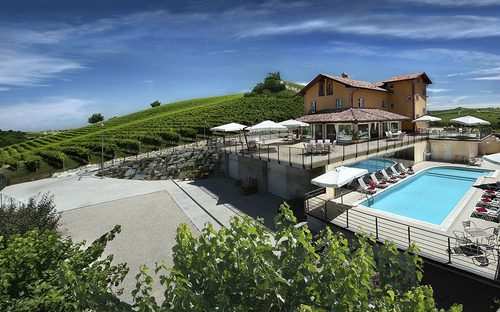 Agriturismo mit Pool und Sonnenschirmen, umgeben von Weinbergen und Natur.