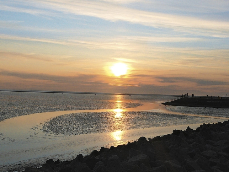Sonnenuntergang über dem Meer bei Büsum mit Wolken und Wasserspiegelung