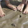 Zwei Paar Kinderfüße im Sand am Strand.
