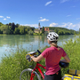 Radfahrerin genießt Ausblick am Tauernradweg entlang eines Flusses.
