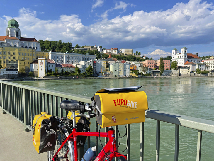 Fahrrad mit Eurobike-Tasche auf Brücke, Blick auf Stadt am Fluss Passau.