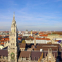 Blick auf das Münchner Rathaus mit Stadt im Hintergrund bei klarem Himmel.