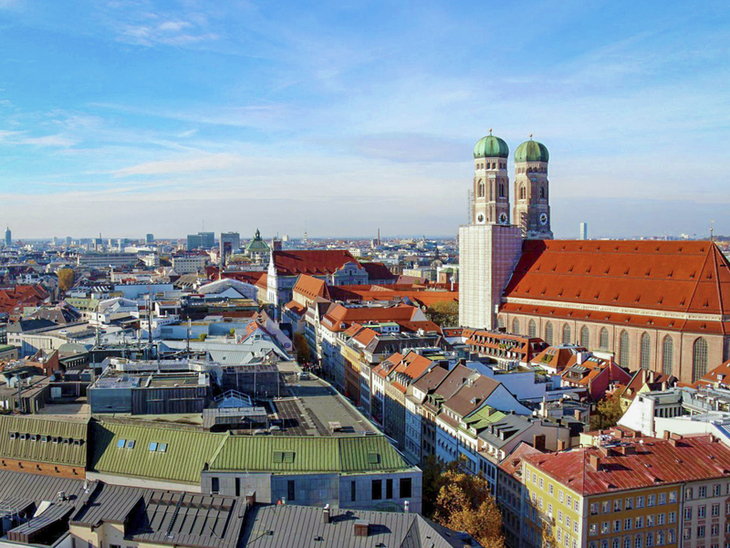 Blick über München mit der Frauenkirche bei klarem Himmel.