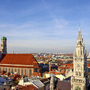 Blick auf Münchens Frauenkirche und Rathaus bei blauem Himmel.