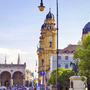 Odeonsplatz in München mit Theatinerkirche und Brunnen, sonniges Wetter.