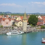 Blick auf Lindau am Bodensee mit Hafen, Booten und historischen Gebäuden unter leicht bewölktem Himmel.