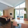 Helles Wohnzimmer mit Essbereich, Sofas, Tisch, großen Fenstern, modernen Möbeln.