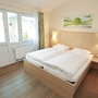 Helles Schlafzimmer mit Doppelbett und großem Fenster.