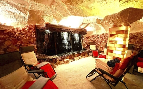 Beleuchtete Salzgrotte mit Liegestühlen und Wasserfall.
