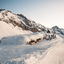 Winterliche Berglandschaft mit Schneebauten und Personen im Iglu-Dorf.