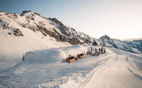 Winterliche Berglandschaft mit Schneebauten und Personen im Iglu-Dorf.