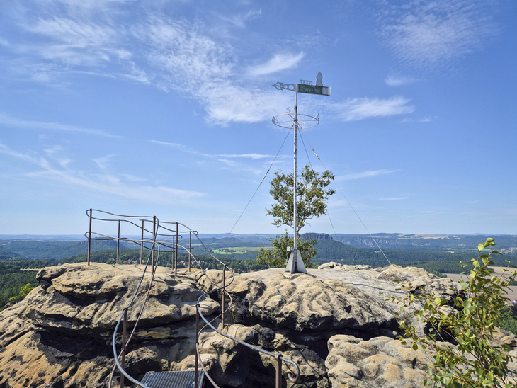 Aussicht vom Gohrisch mit Wetterfahne und Felsen unter blauem Himmel