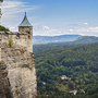 Festung Königstein mit Blick über bewaldete Hügel und das Elbsandsteingebirge.