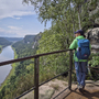 Wanderin auf Aussichtsplattform mit Blick auf Fluss und Felsen im Malerweggebiet.