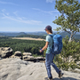 Wanderer mit Rucksack auf dem Malerweg mit Aussicht auf bewaldete Landschaft.