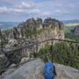 Blick von einer Aussichtsplattform auf Felsformationen des Malerwegs, mit Rucksack im Vordergrund.