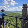 Eine Person wandert mit Rucksack und Wanderstöcken am Aussichtspunkt Pfaffenstein.