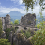 Blick auf die Basteibrücke im Elbsandsteingebirge mit umliegenden Felsen und Wald.