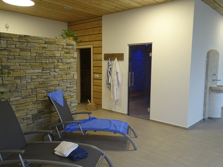 Entspannungsbereich mit Liegen und Bademänteln in modernem Spa.