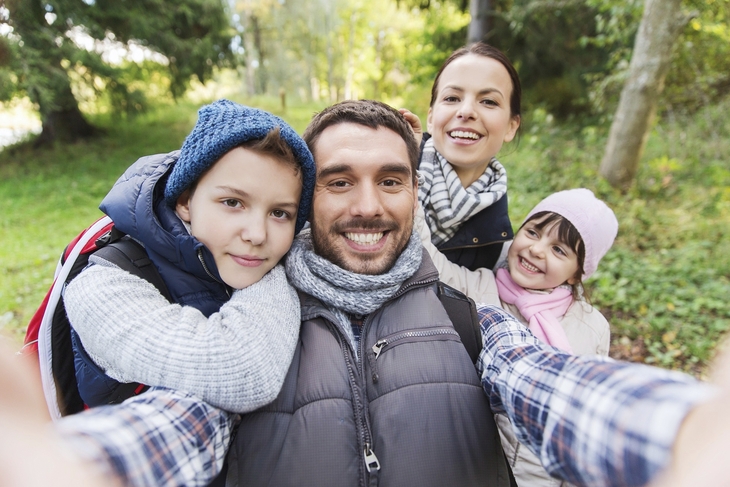 Eine Familie macht ein Selfie im Wald.