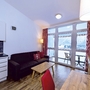 Wohnzimmer mit Küche in Ferienwohnung, Holzboden, Sofa und Fenster mit Bergblick.