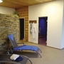 Ruheraum mit Liegestühlen, Bademänteln an der Wand und Natursteinwand.