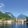 Stadt Riva del Garda am See mit Bergen im Hintergrund bei klarem Himmel.