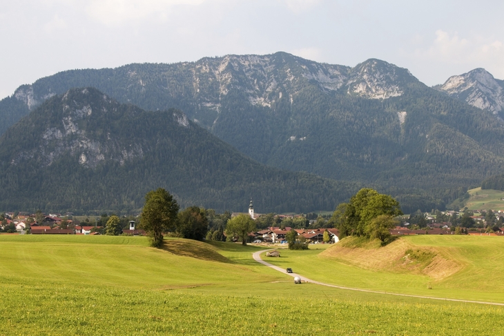 Dorf Inzell vor Alpenkulisse mit grünen Wiesen und bewaldeten Bergen.